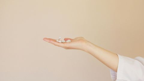 A person is holding a handful of pills in their hand.