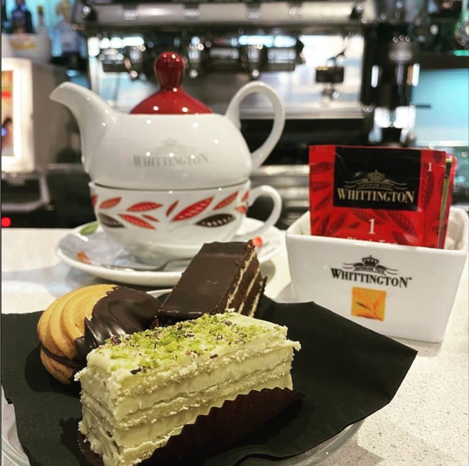 Una scatola di tè Whittington è accanto a un piatto di dessert