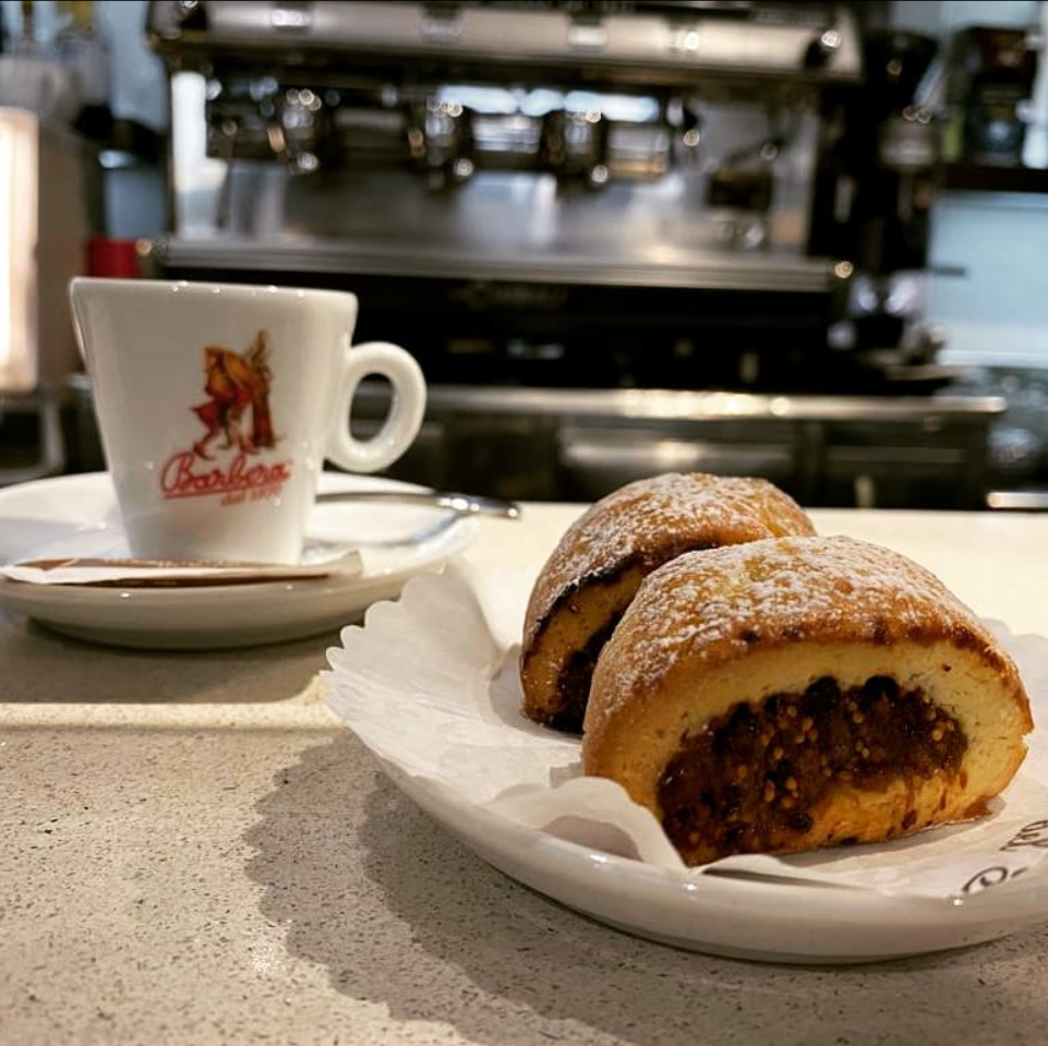 Due pasticcini su un piatto accanto a una tazza di caffè