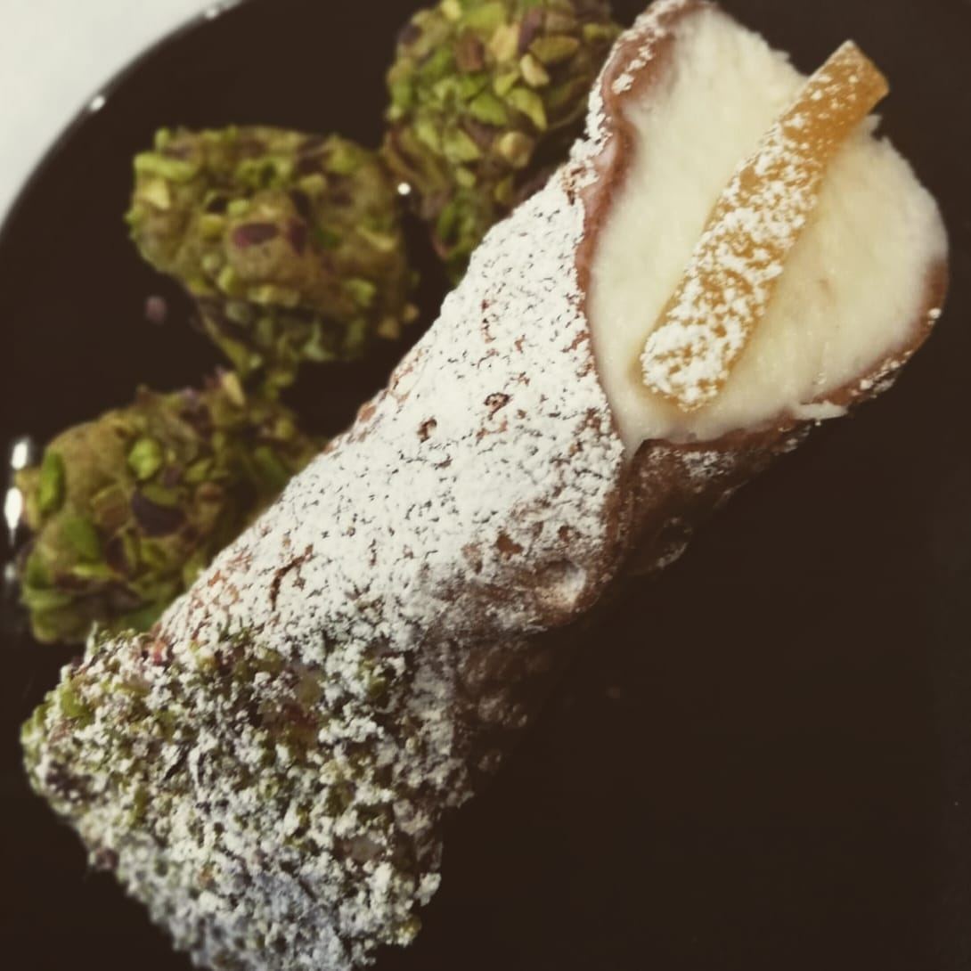 Un primo piano di un cannolo con zucchero a velo su un piatto