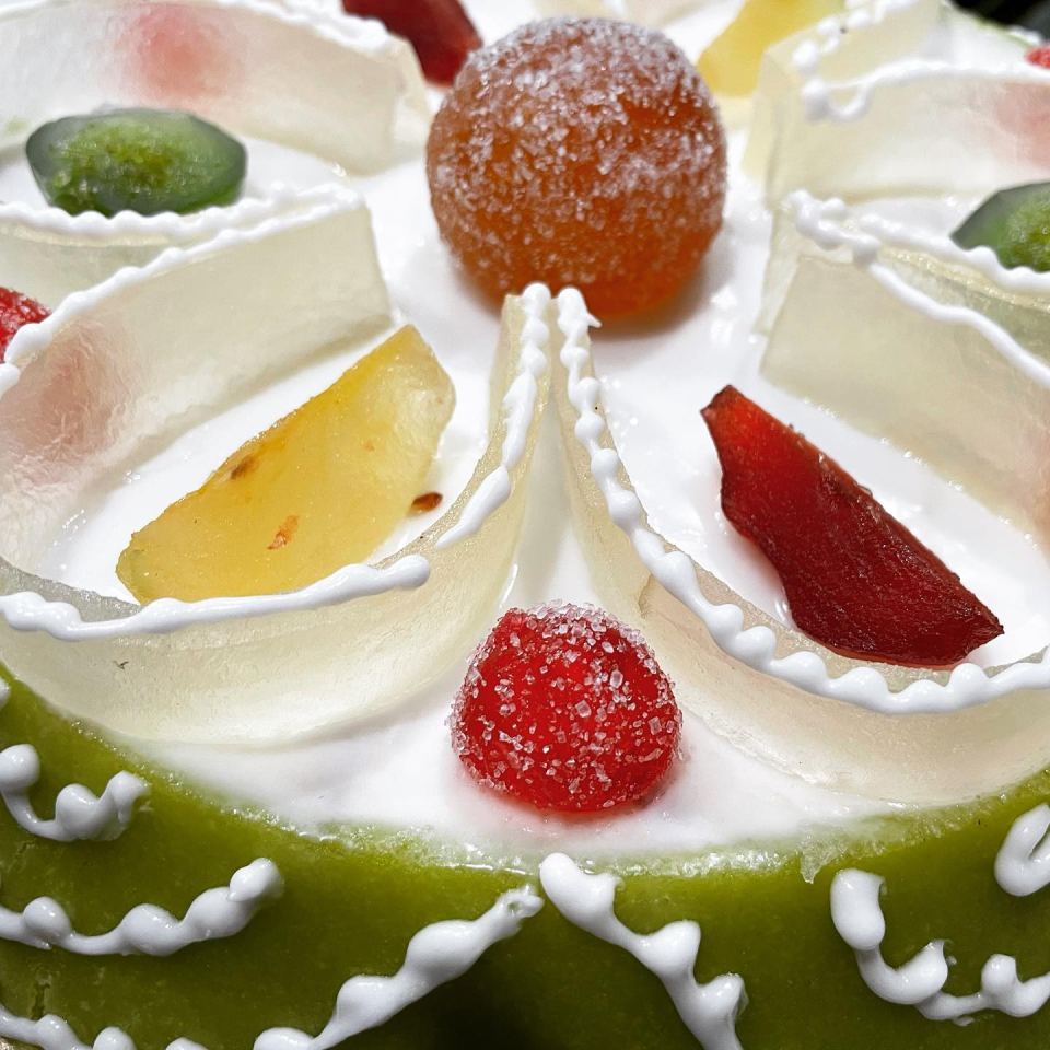 Una torta verde con glassa bianca e frutta sopra