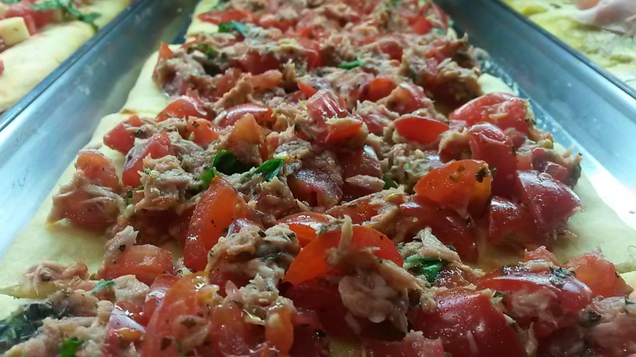 Un primo piano di una pizza con pomodori e tonno sopra