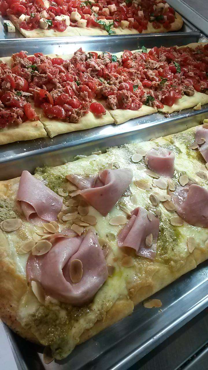 Un vassoio di pizze con prosciutto e pomodori sopra