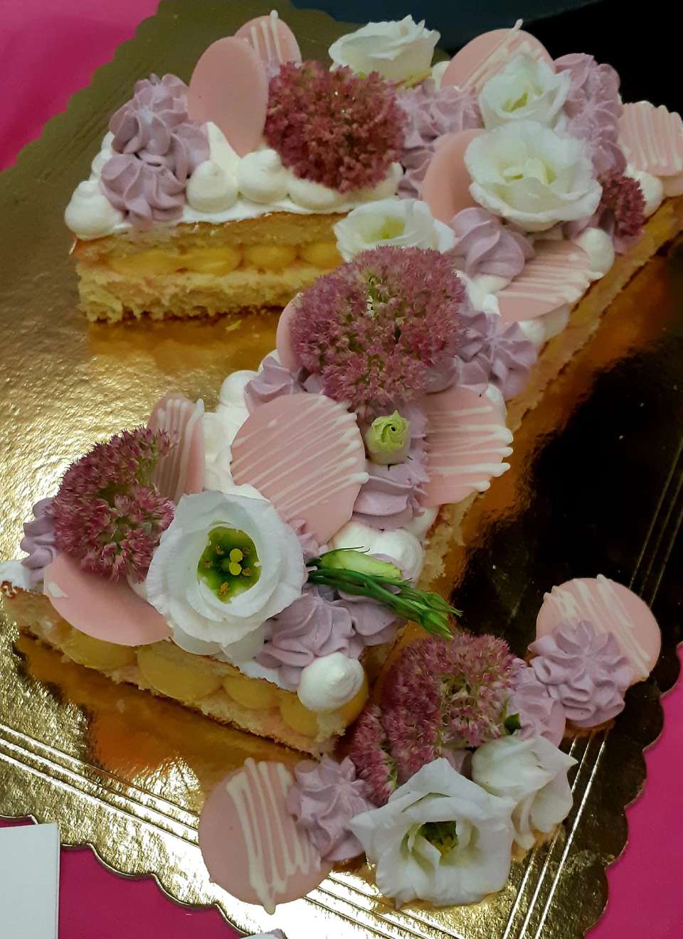 Una torta a forma di lettera l decorata con fiori rosa e bianchi