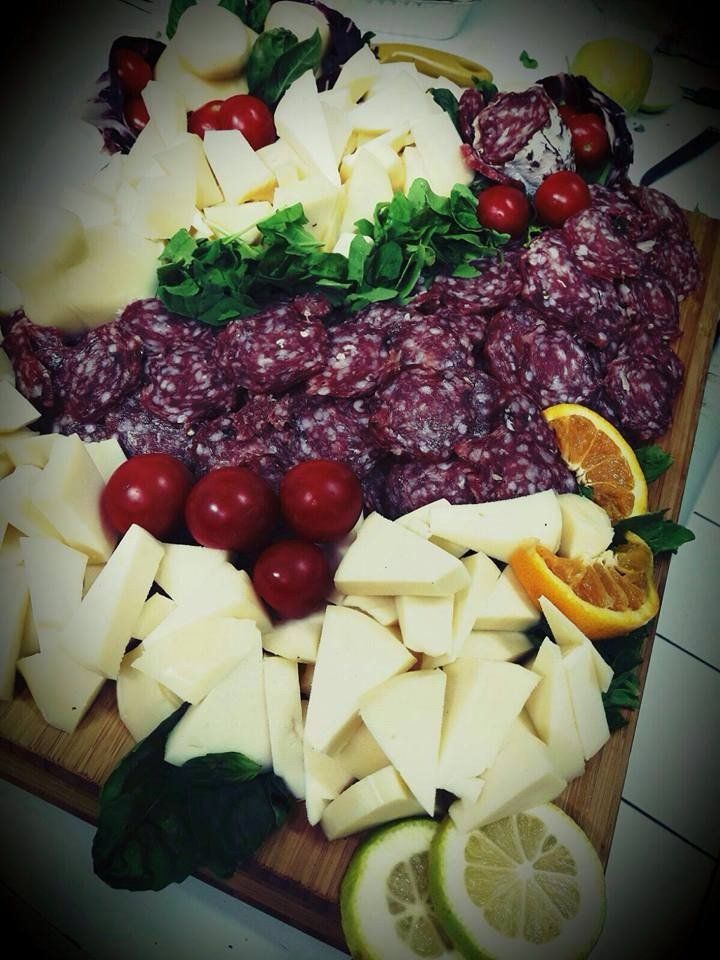 Un tagliere con carne, formaggio e pomodori sopra