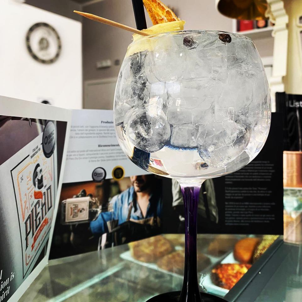 Un bicchiere pieno di ghiaccio è appoggiato su un tavolo accanto a un cartello che dice picho