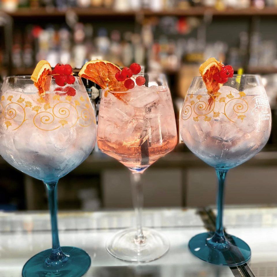 Tre bicchieri da vino pieni di ghiaccio e un drink su un tavolo.