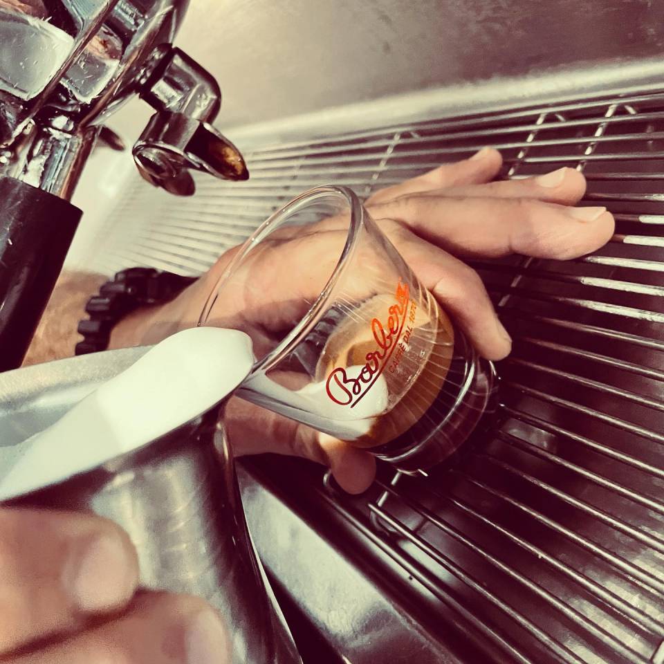 Una persona versa latte in un bicchiere su cui è scritto barista