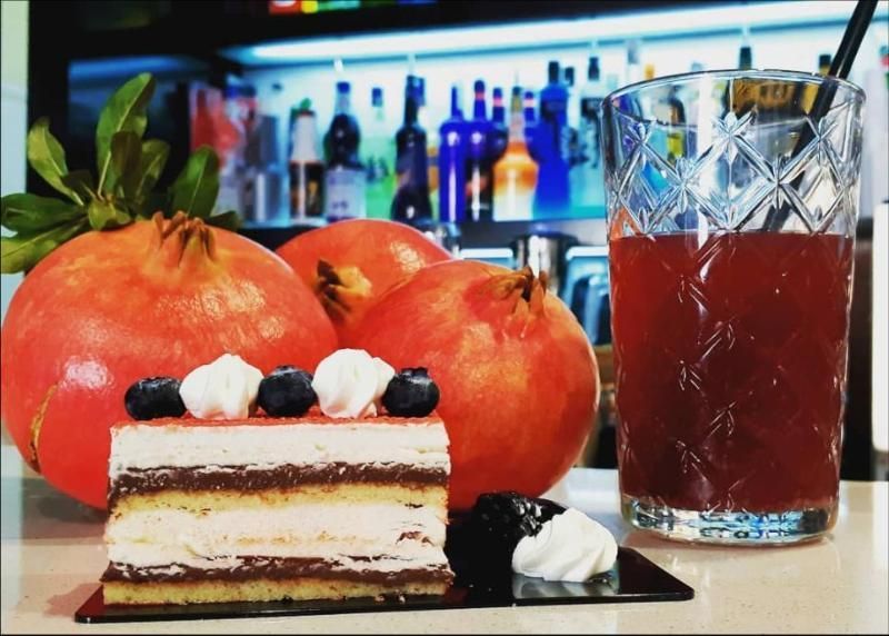 Una torta e una bevanda sono su un tavolo con melograni sullo sfondo