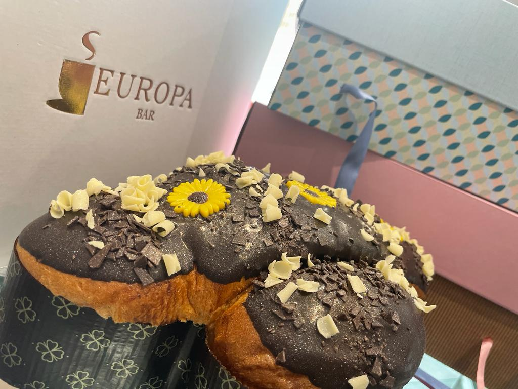 Un primo piano di una colomba al cioccolato con un fiore giallo sopra