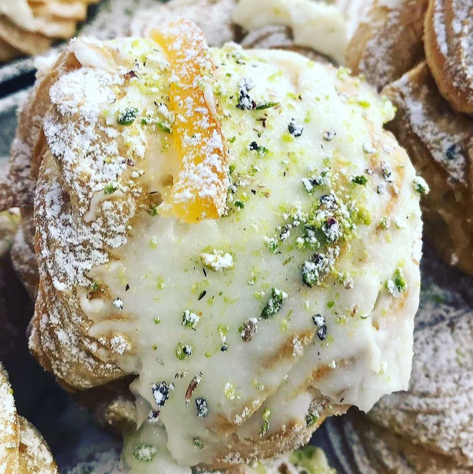 Un primo piano di un dolce con zucchero a velo e pistacchi in cima.