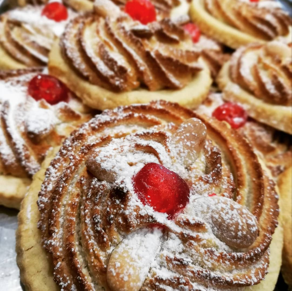 Un primo piano di un biscotto con zucchero a velo e una ciliegia in cima