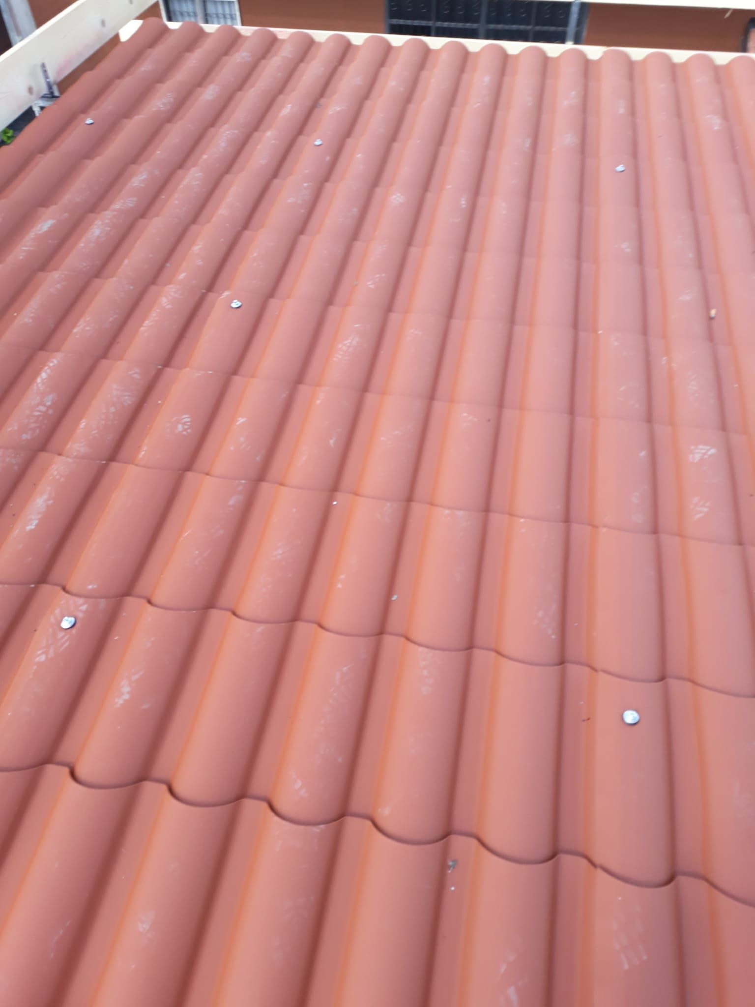 Primo piano di un tetto di tegole rosse con viti.