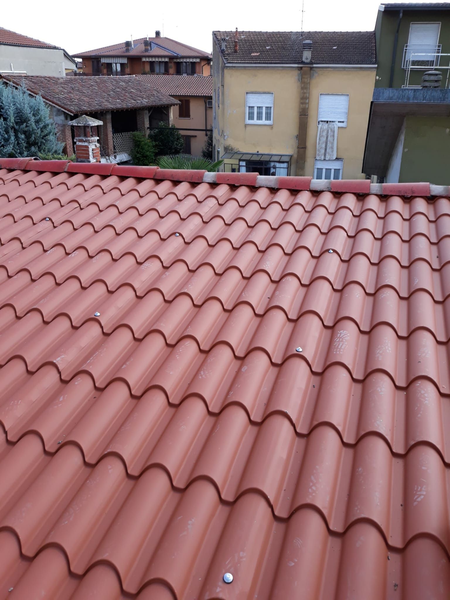 Un tetto di tegole rosse con un edificio giallo sullo sfondo