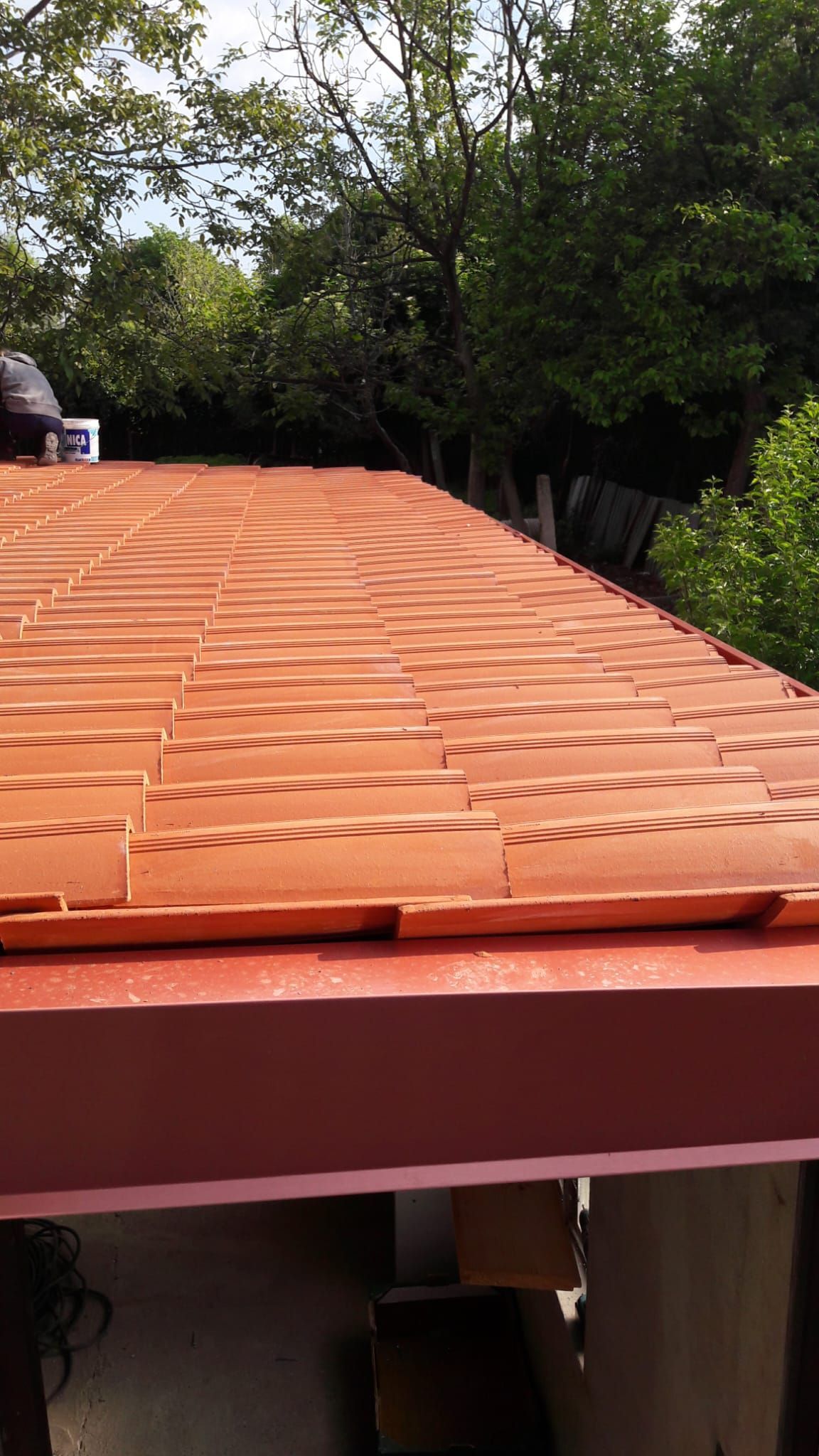 Un tetto con tante tegole e alberi sullo sfondo.