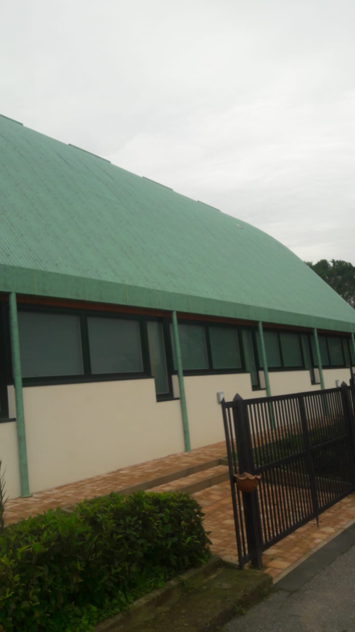Un edificio con un tetto verde e una recinzione di fronte