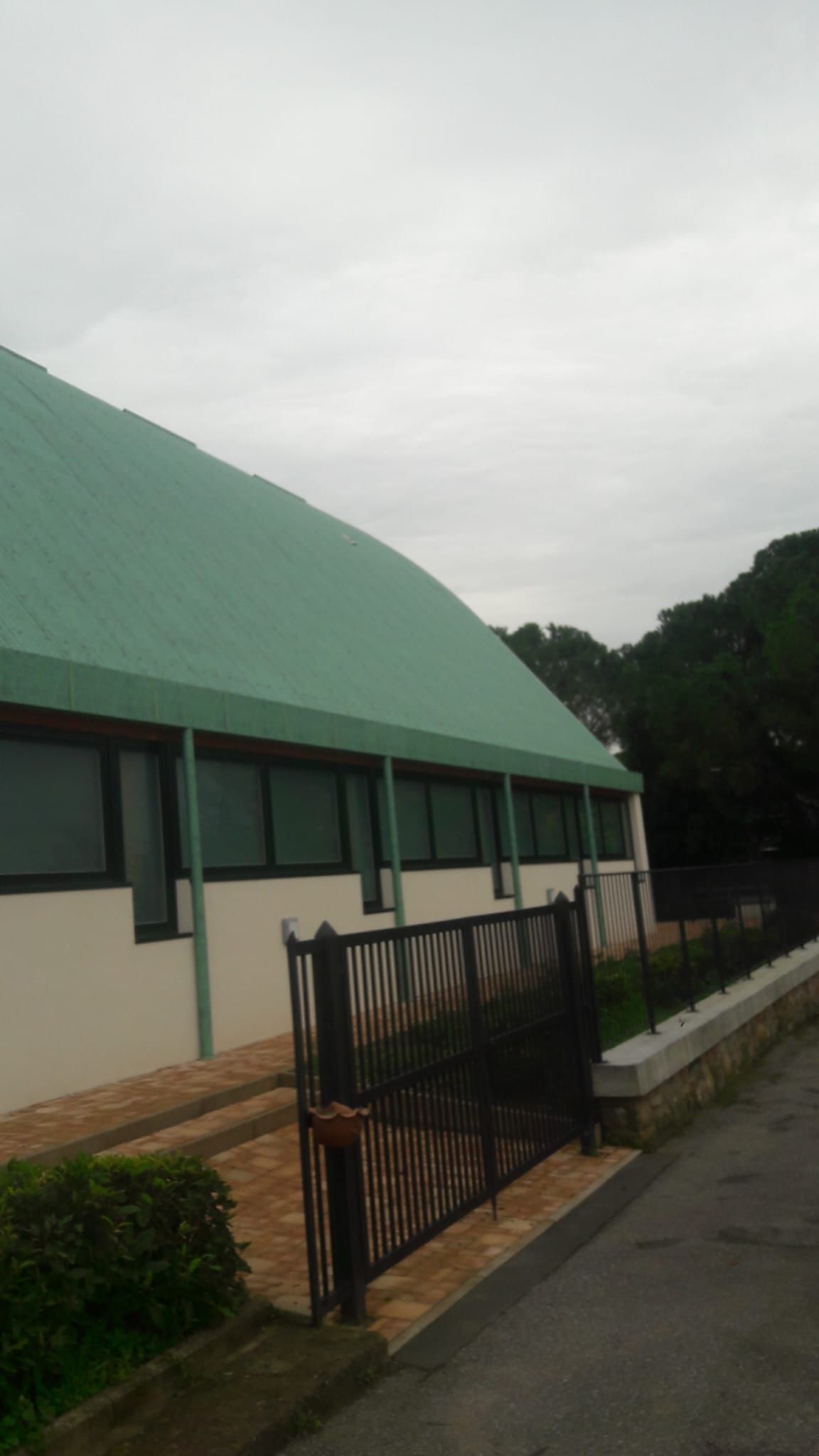 Un edificio con un tetto verde e una recinzione di fronte