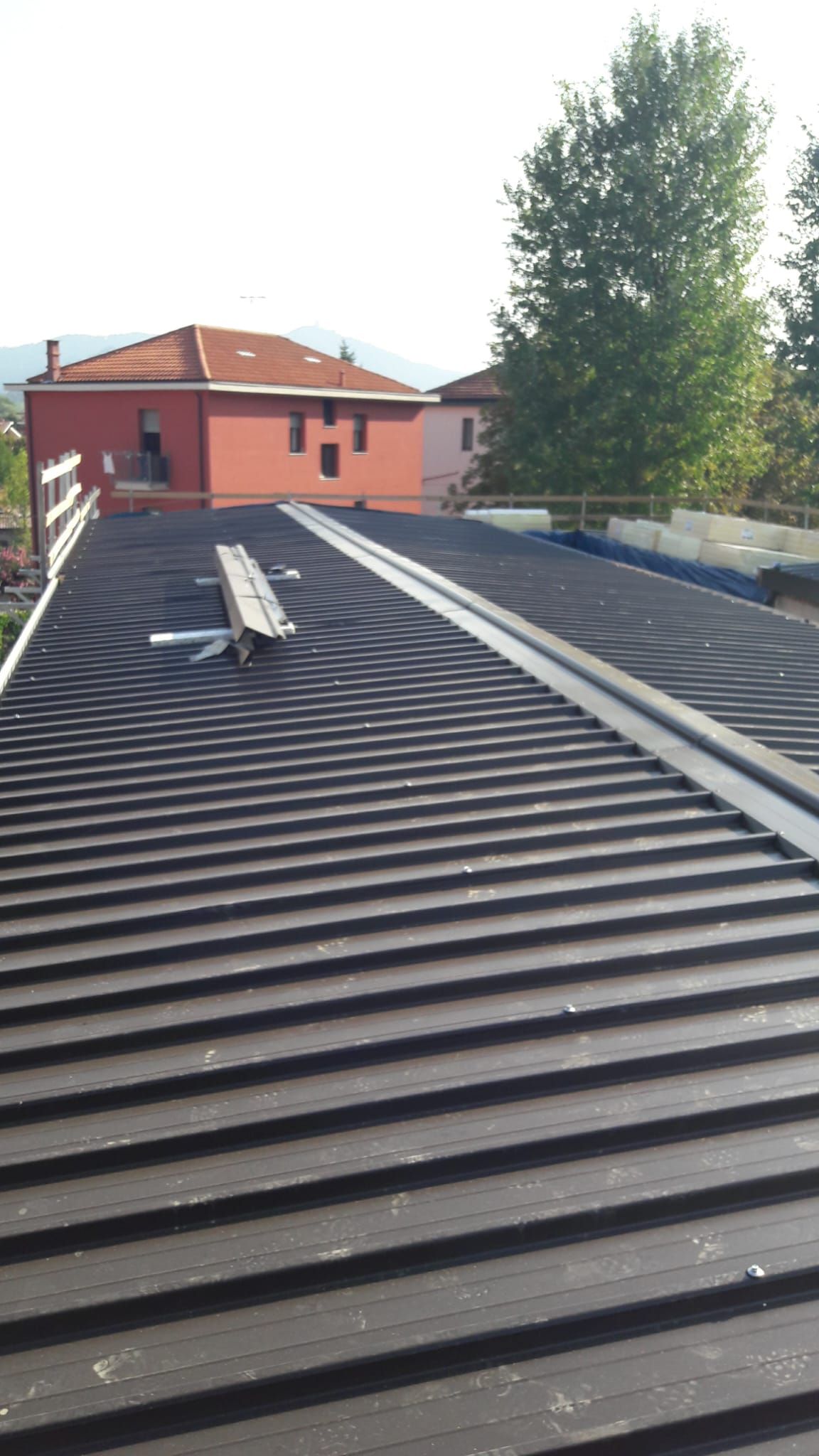 Un primo piano di un tetto con una casa rossa sullo sfondo