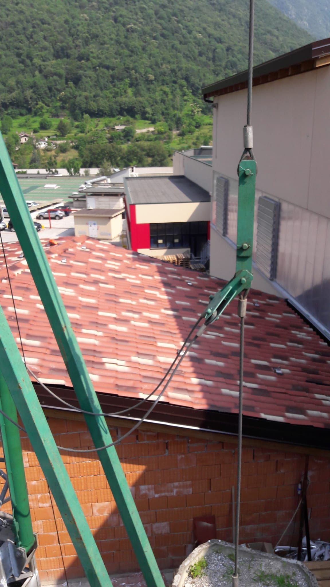 Una gru verde è appesa al lato di un edificio.