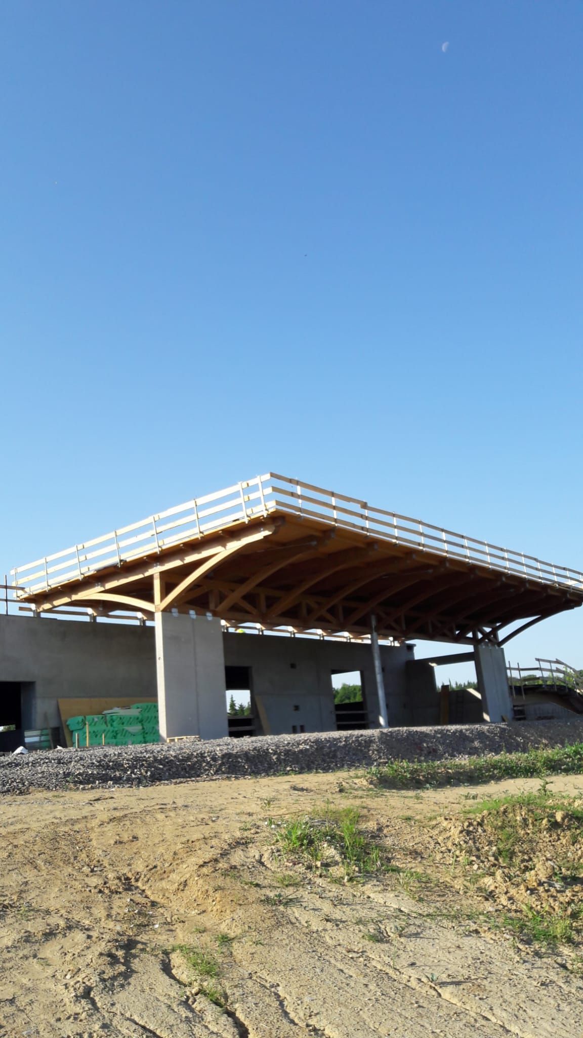 Un edificio in costruzione con un tetto in legno e un cielo azzurro sullo sfondo.