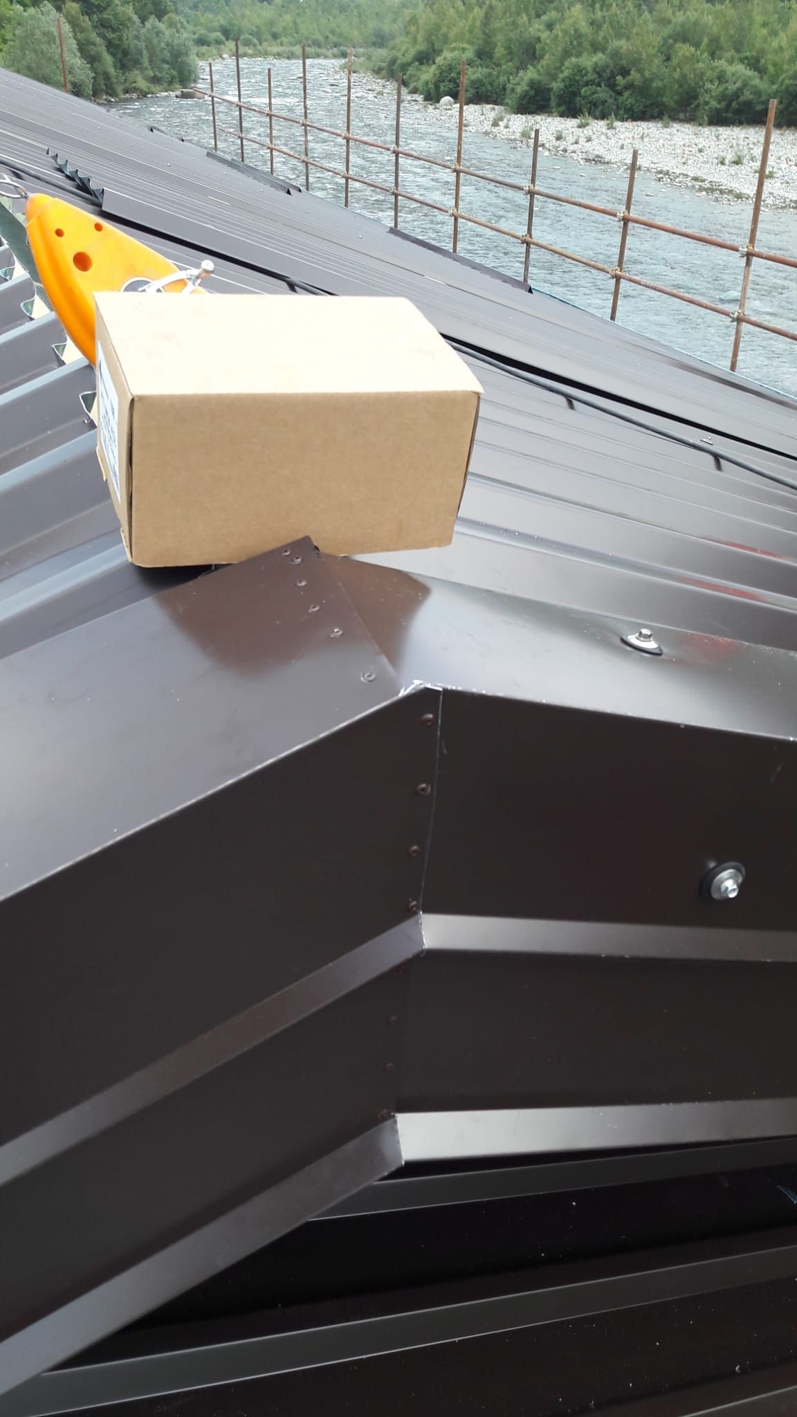 Una scatola di cartone è appoggiata su un tetto di metallo.