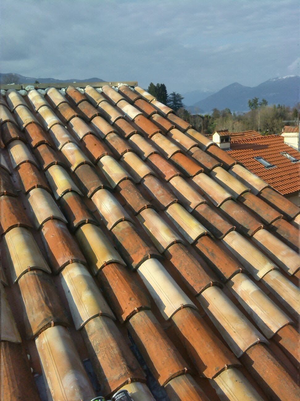 Un primo piano di un tetto di tegole con montagne sullo sfondo