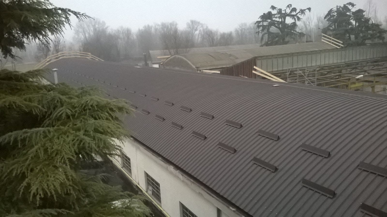 Un grande edificio con il tetto coperto di neve e alberi sullo sfondo.