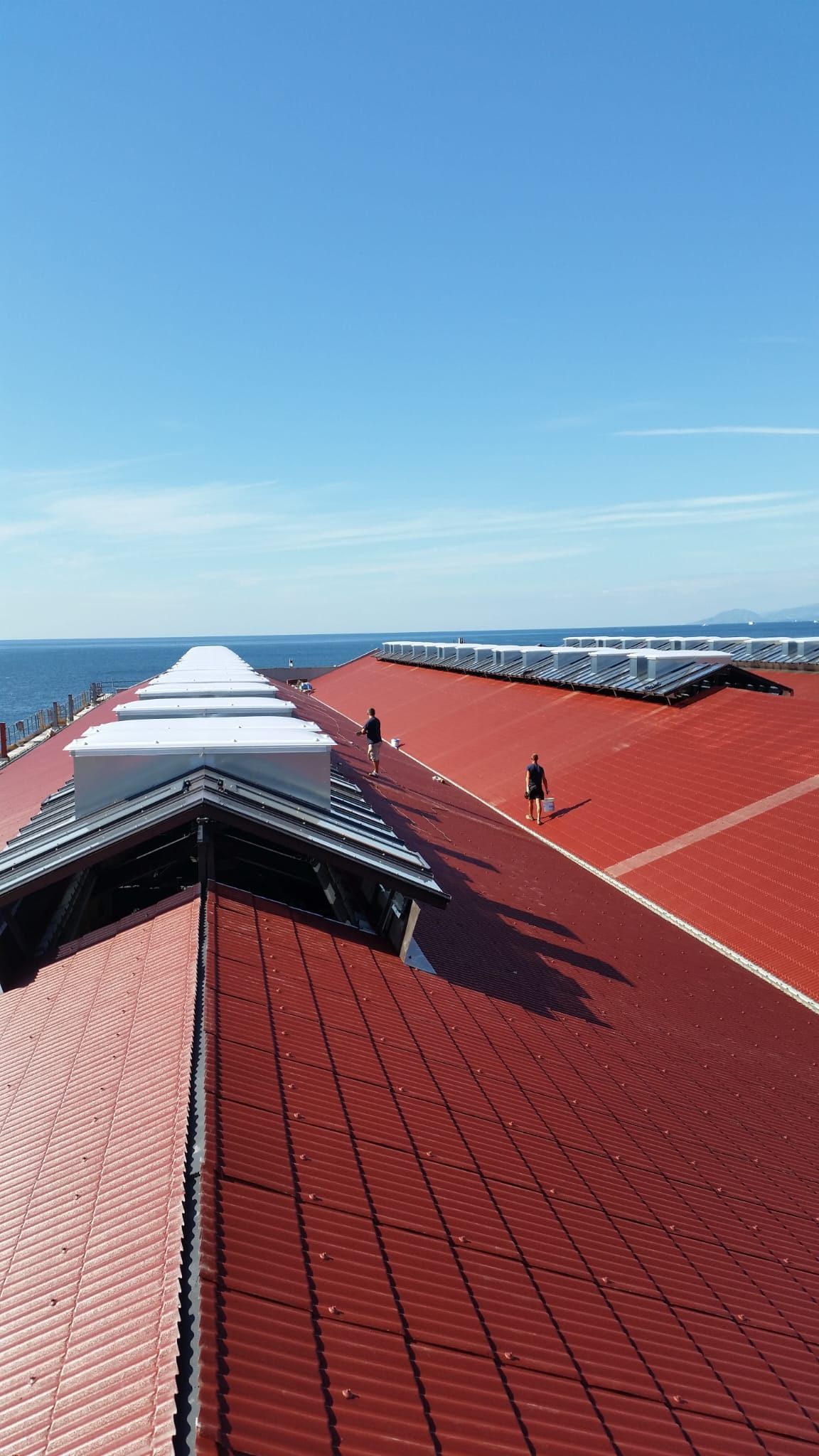 Un gruppo di persone cammina sul tetto di un edificio che si affaccia sull'oceano.