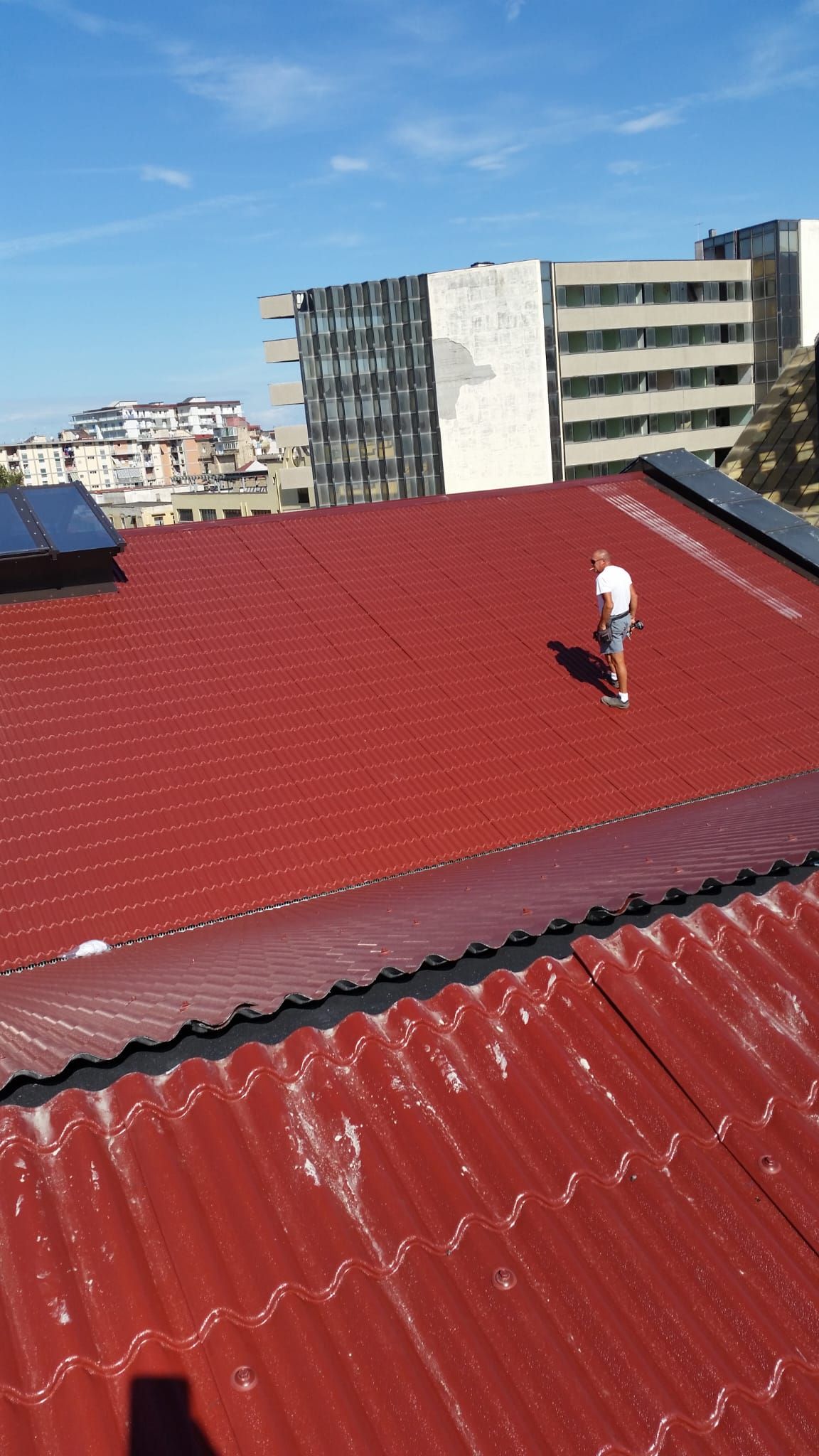 Un uomo è in piedi in cima a un tetto rosso.