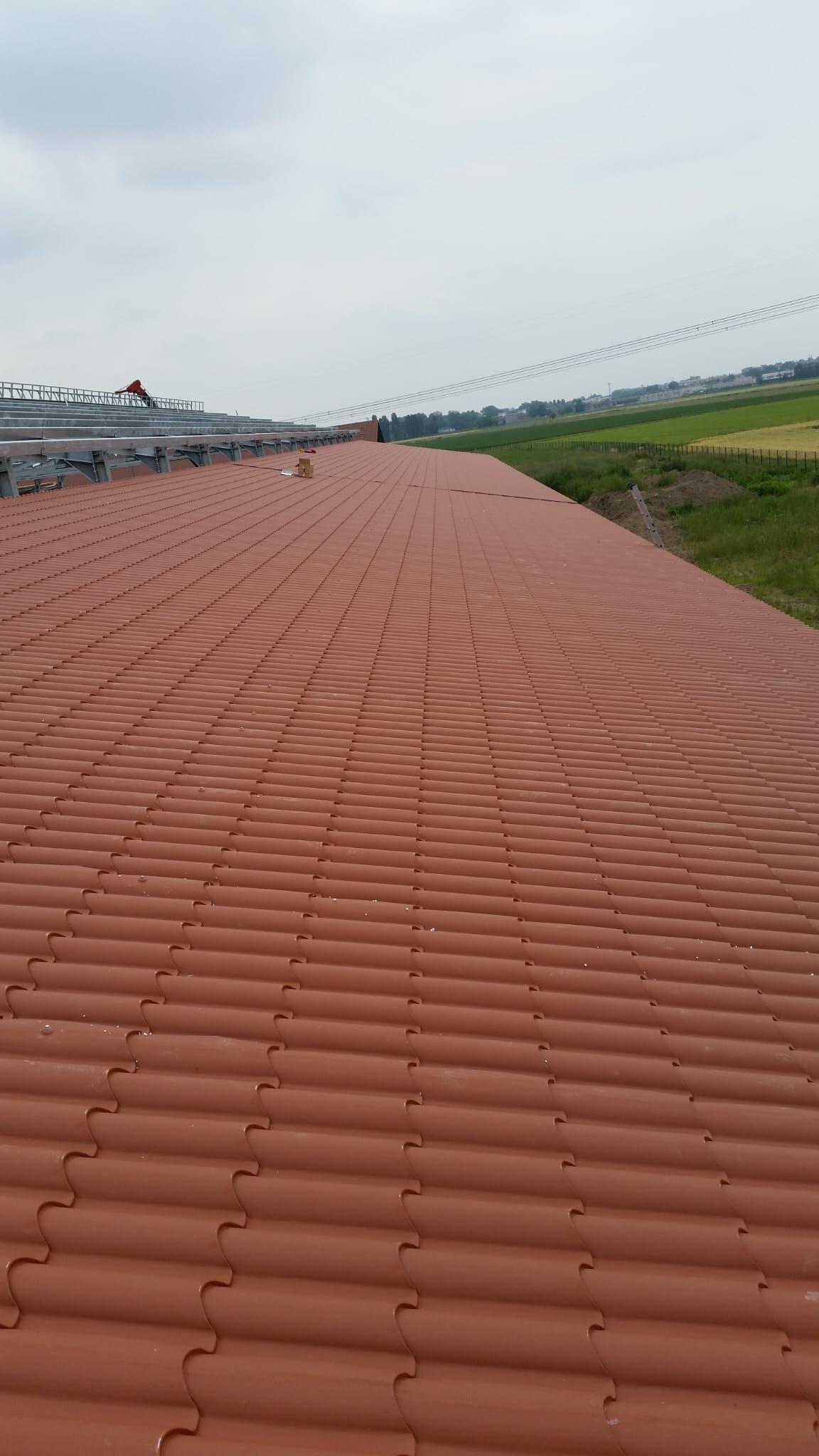 Un primo piano di un tetto di tegole rosse con un campo sullo sfondo.
