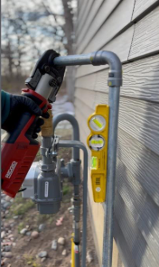 A person is installing a gas meter on the side of a house.