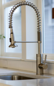 A kitchen sink with a stainless steel faucet and a window in the background
