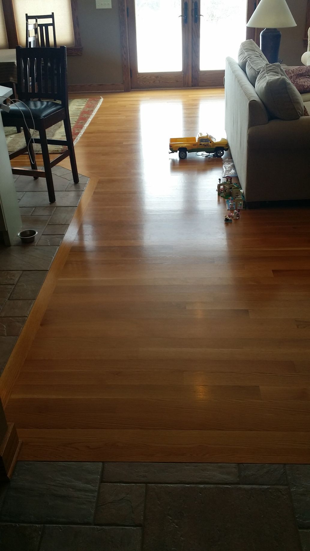 A wooden floor in a living room with a couch and chairs.