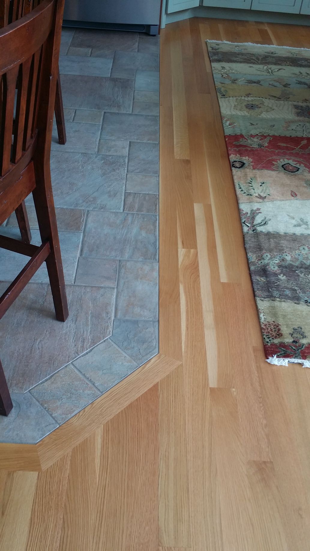 A wooden floor with a rug on it in a kitchen.