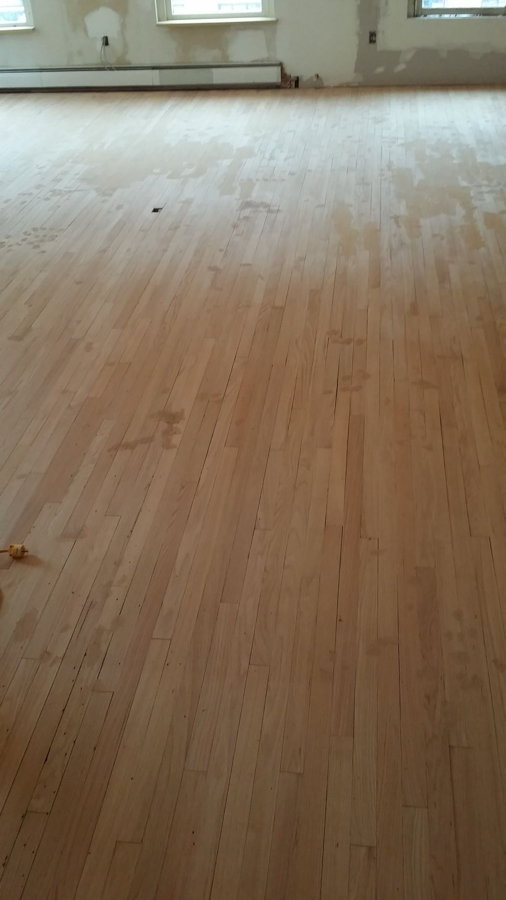 A large empty room with a wooden floor and a window.