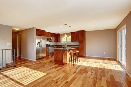 A kitchen with hardwood floors and stainless steel appliances in an empty house.