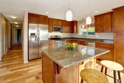 A kitchen with wooden cabinets , granite counter tops , stainless steel appliances and a large island.