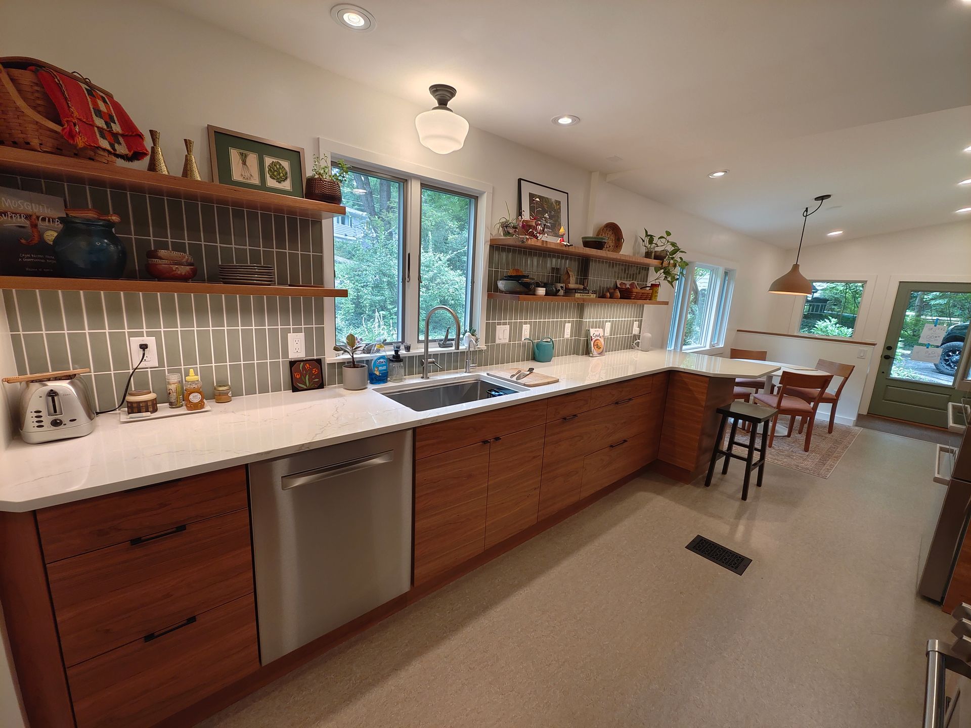 A kitchen with wooden cabinets , white counter tops , a sink and a dishwasher.