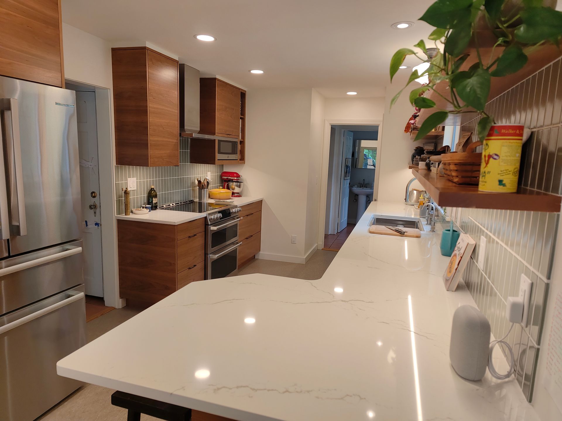 A kitchen with white counter tops , stainless steel appliances , and wooden cabinets.
