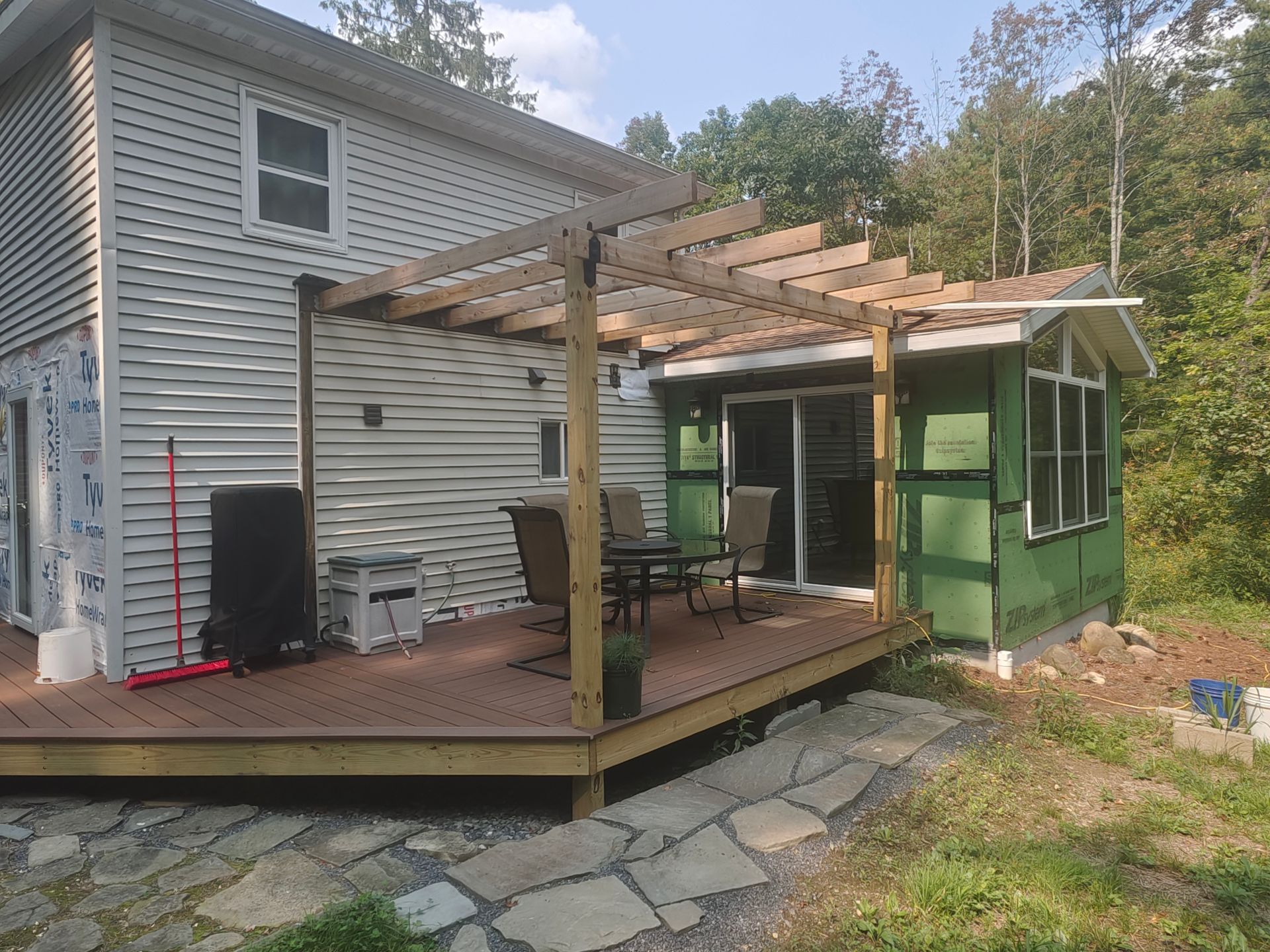 A house with a deck and a pergola in front of it.