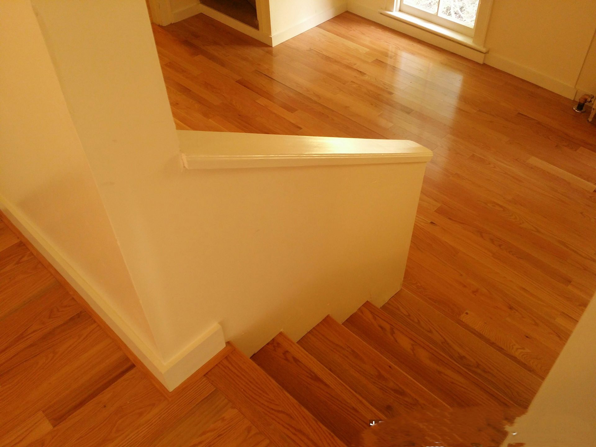 A wooden staircase with a white railing and hardwood floors