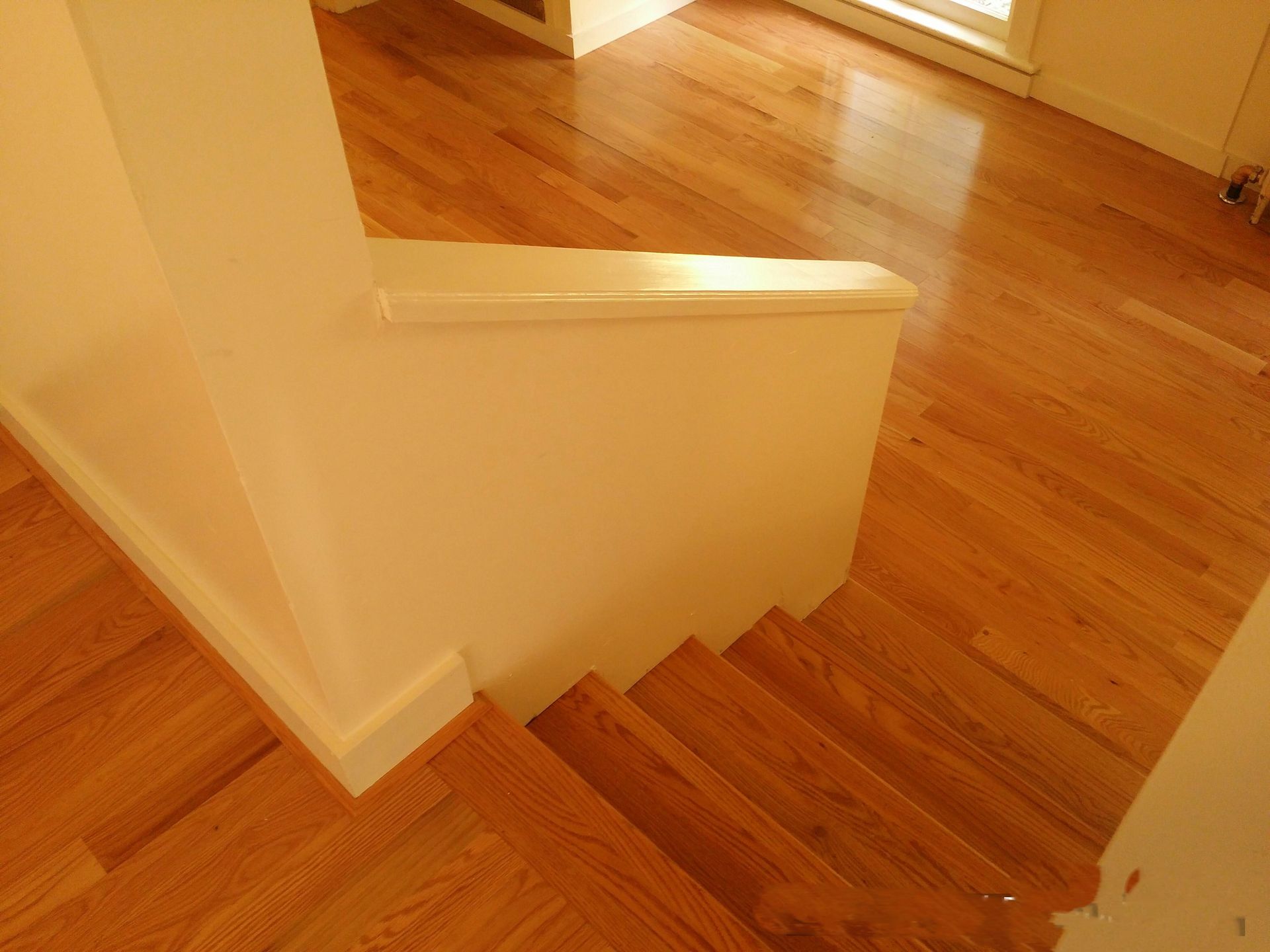 A wooden staircase with a white railing in a house.