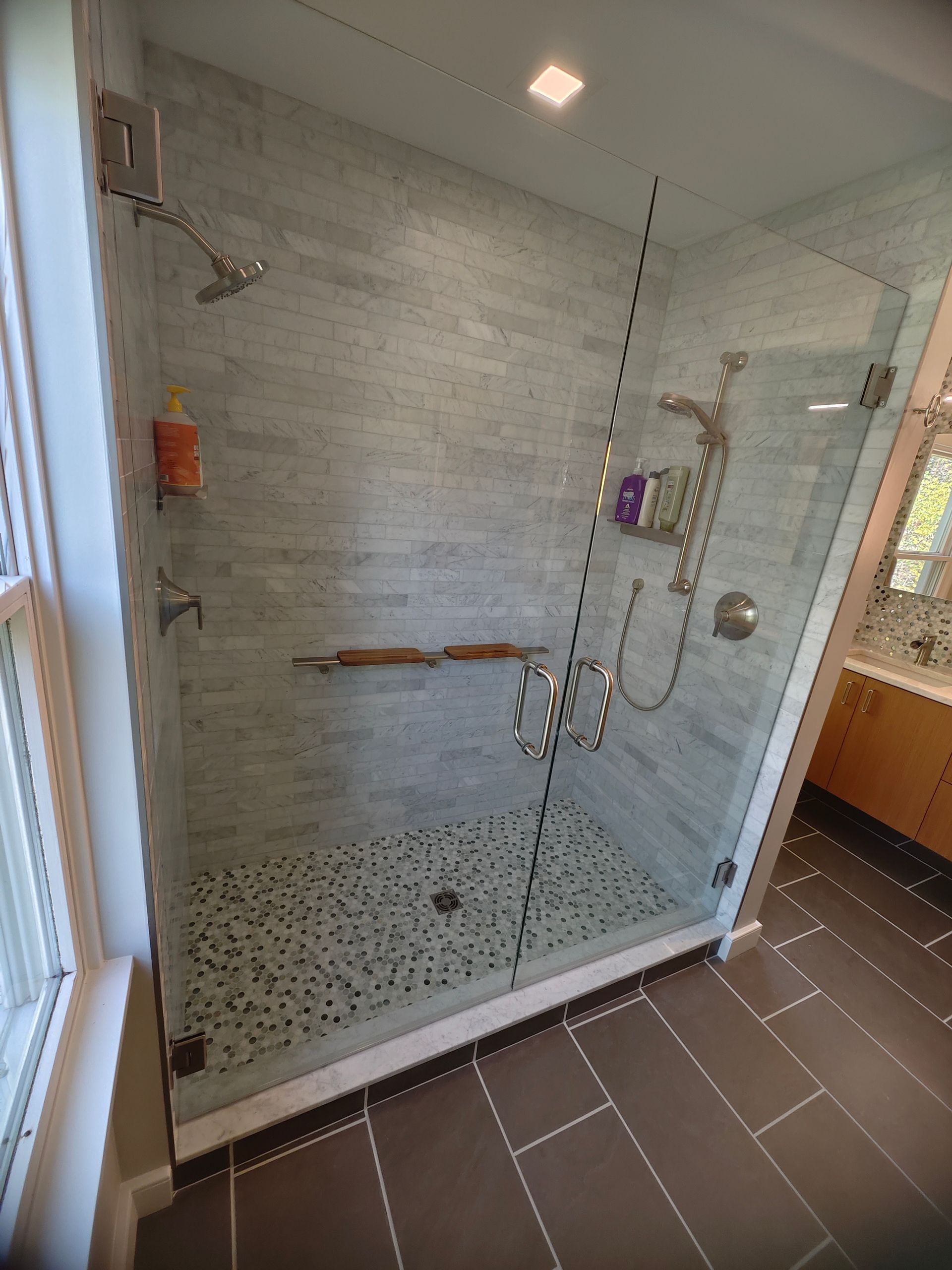 A bathroom with a walk in shower with a glass door.