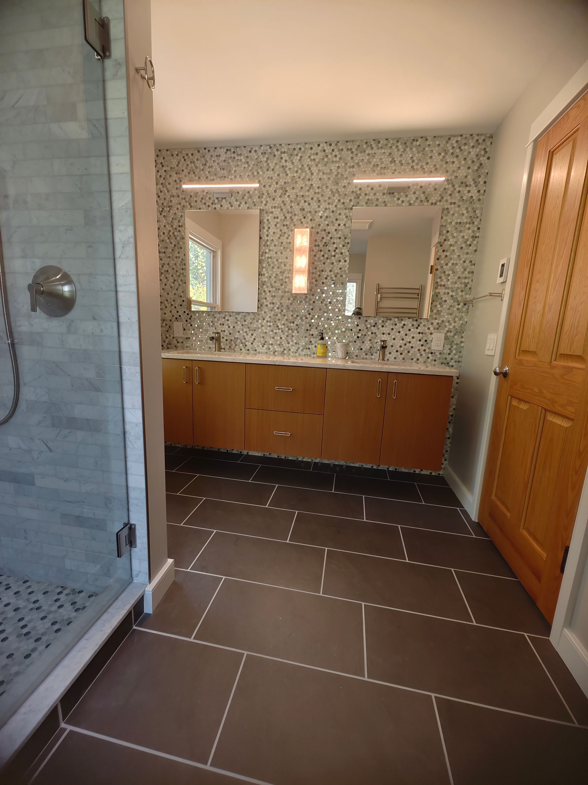 A bathroom with two sinks and a walk in shower