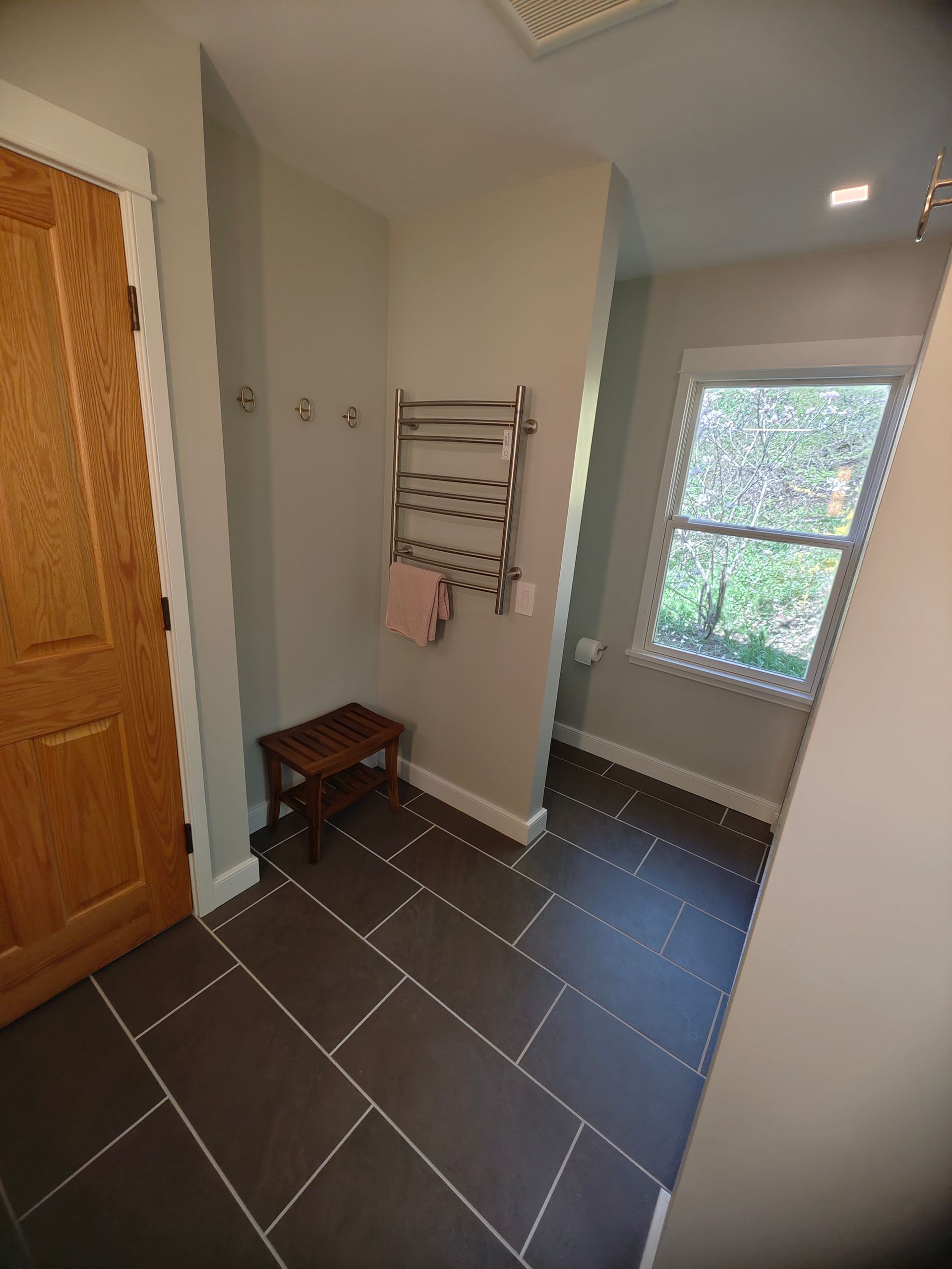 A bathroom with a towel rack on the wall and a window.