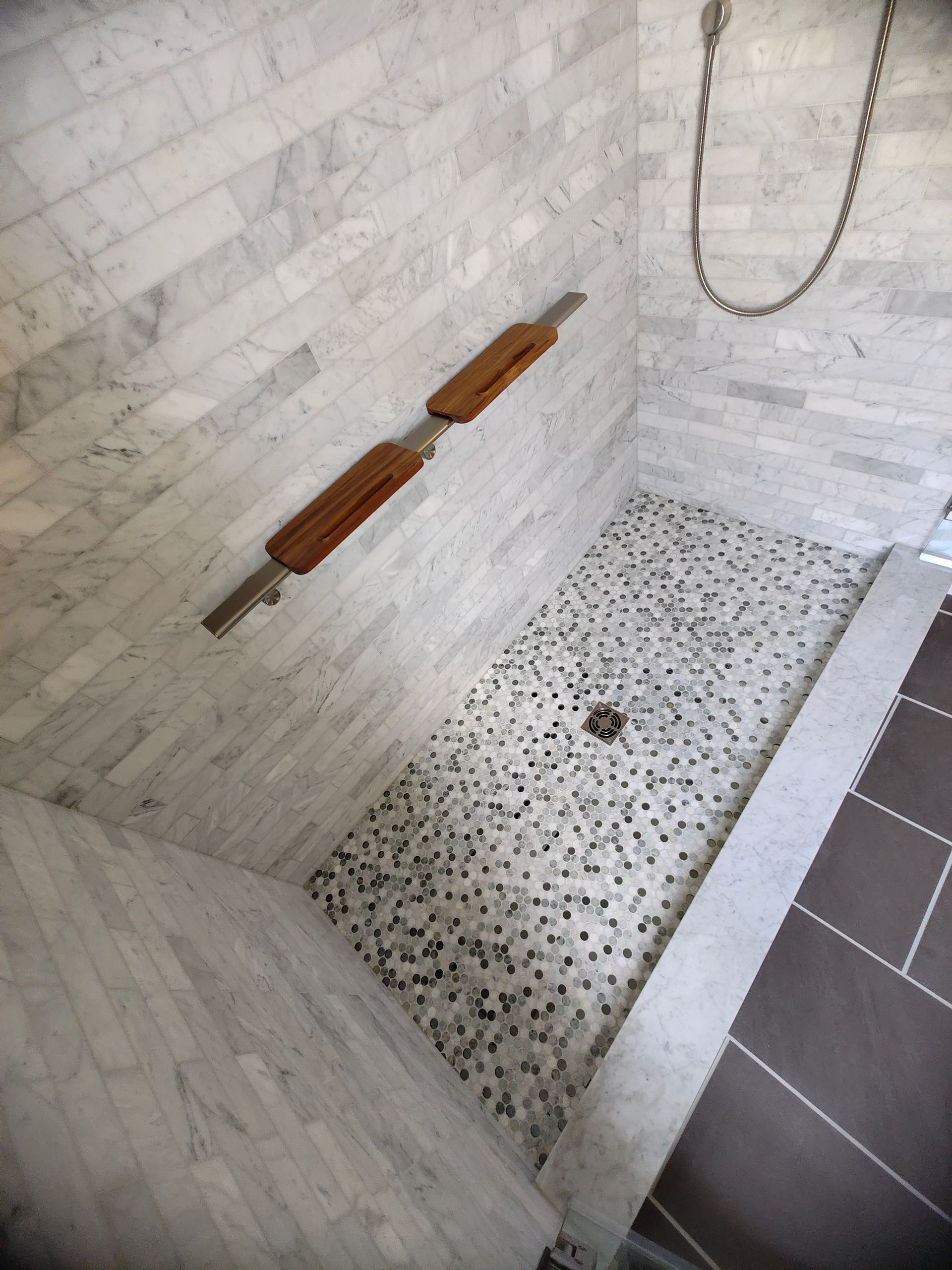 A walk in shower with a tiled floor and wooden shelves
