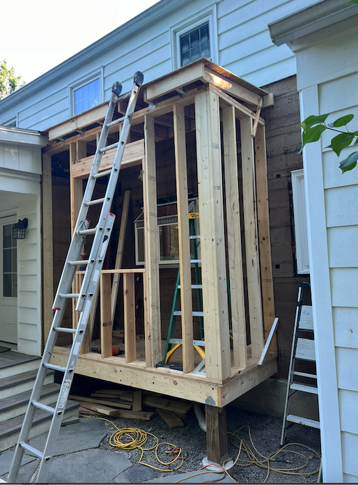 A wooden structure is being built on the side of a house.