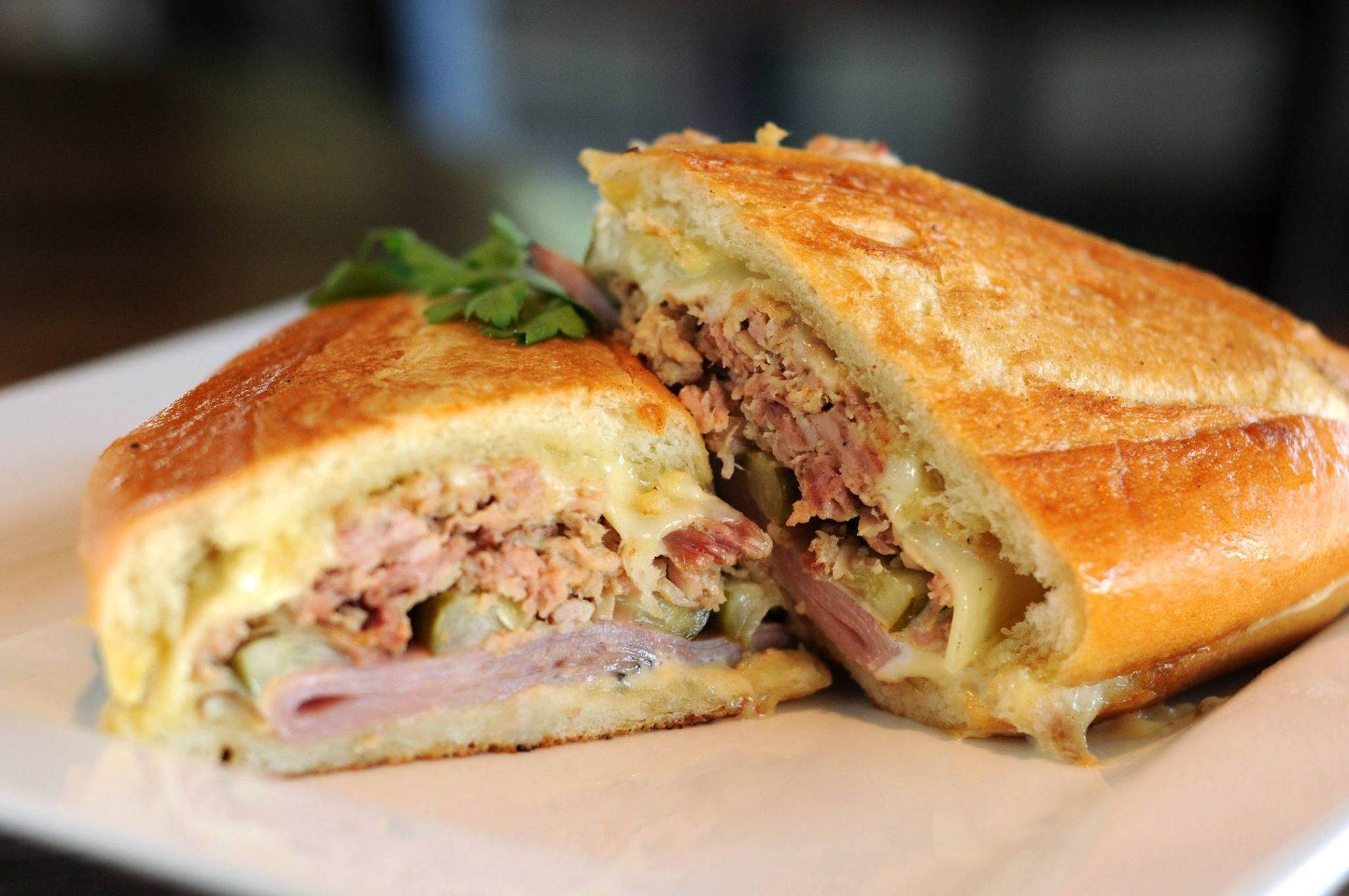 a cuban sandwich is cut in half on a white plate . — Mary Esther, FL — Bella Donna Catering