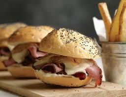 a roast beef sandwich is sitting on a wooden cutting board next to a bucket of french fries . — Mary Esther, FL — Bella Donna Catering