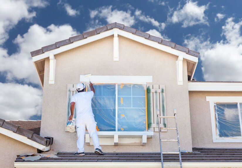 A home painter in Edmond painting a window on the side of a house